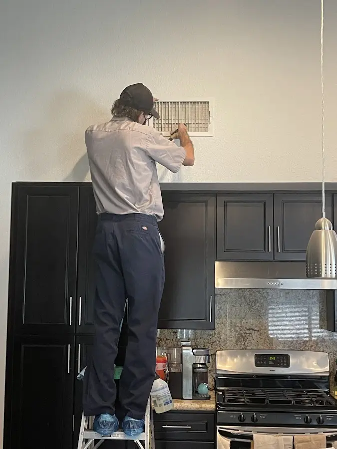 Technician inspecting an air vent during HVAC service in Saratoga Springs